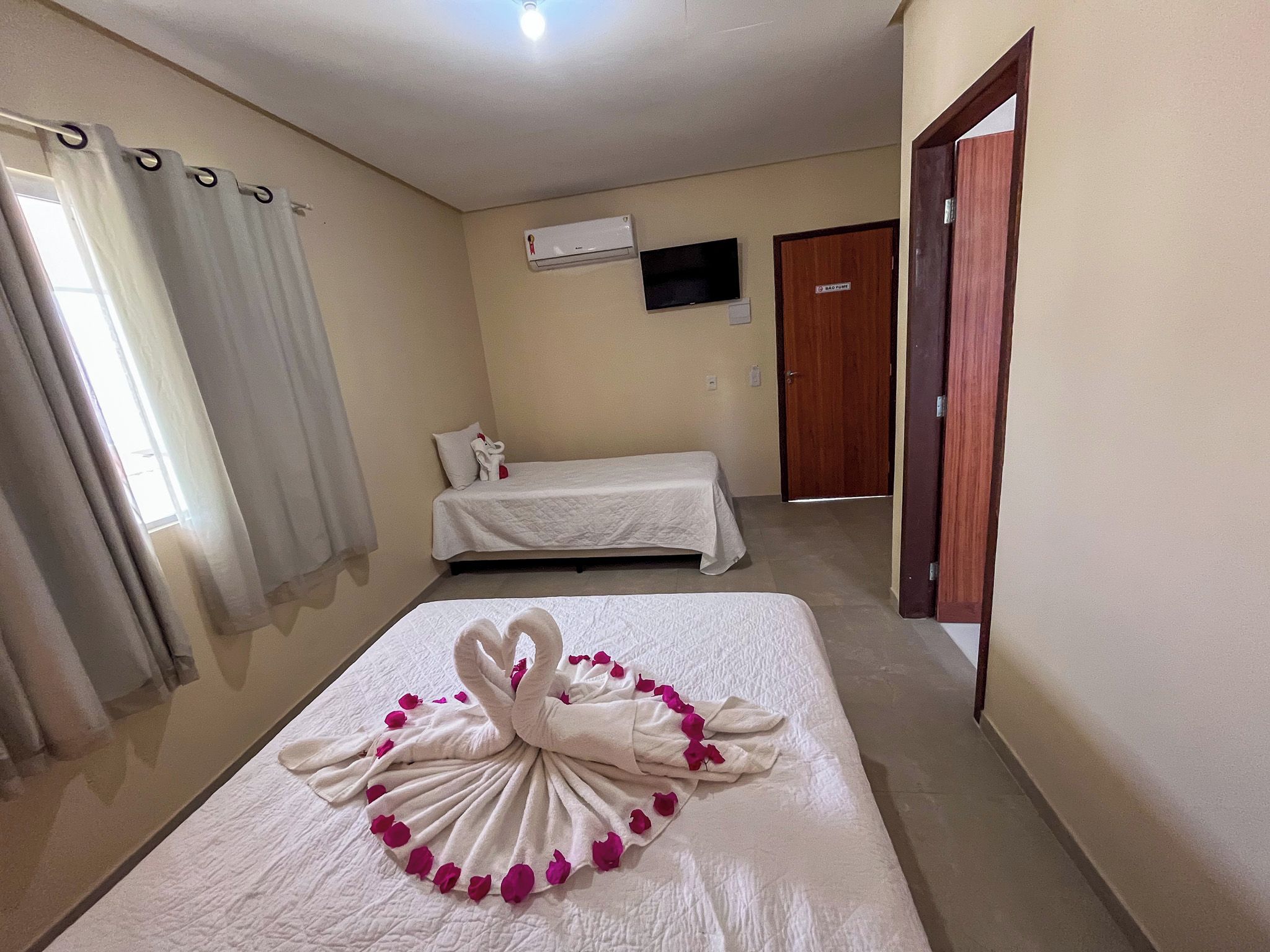 A hotel room with a bed, a TV mounted on the wall, and a door.