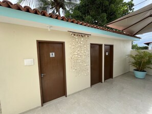 A hotel corridor with three doors, each marked with a "hotel room" sign, a tiled floor, and a potted plant in the corner. - Pousada Donna Maraka (Ipojuca)