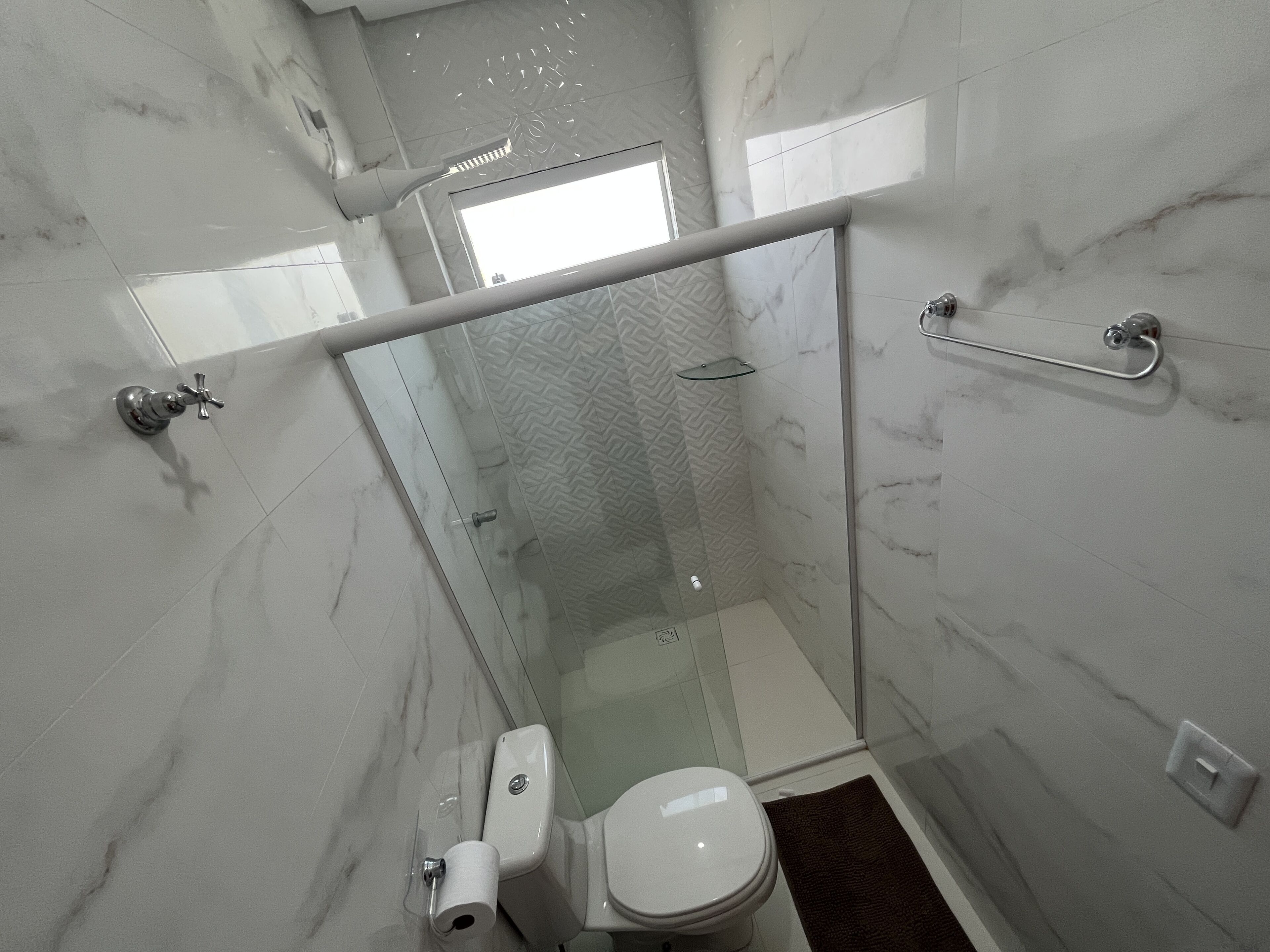 Une salle de bain moderne équipée de toilettes, d’une douche et d’une porte en verre.