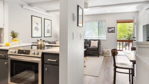 Eine moderne Küche mit Backofen, ein Essbereich mit Tisch und Stühlen sowie ein Wohnbereich mit Sofa und einem Fenster mit Jalousien.