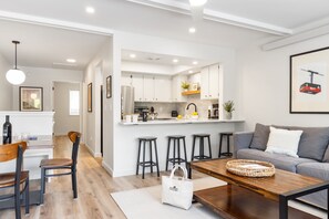 Una cocina moderna con armarios blancos, una isla central y taburetes de bar.