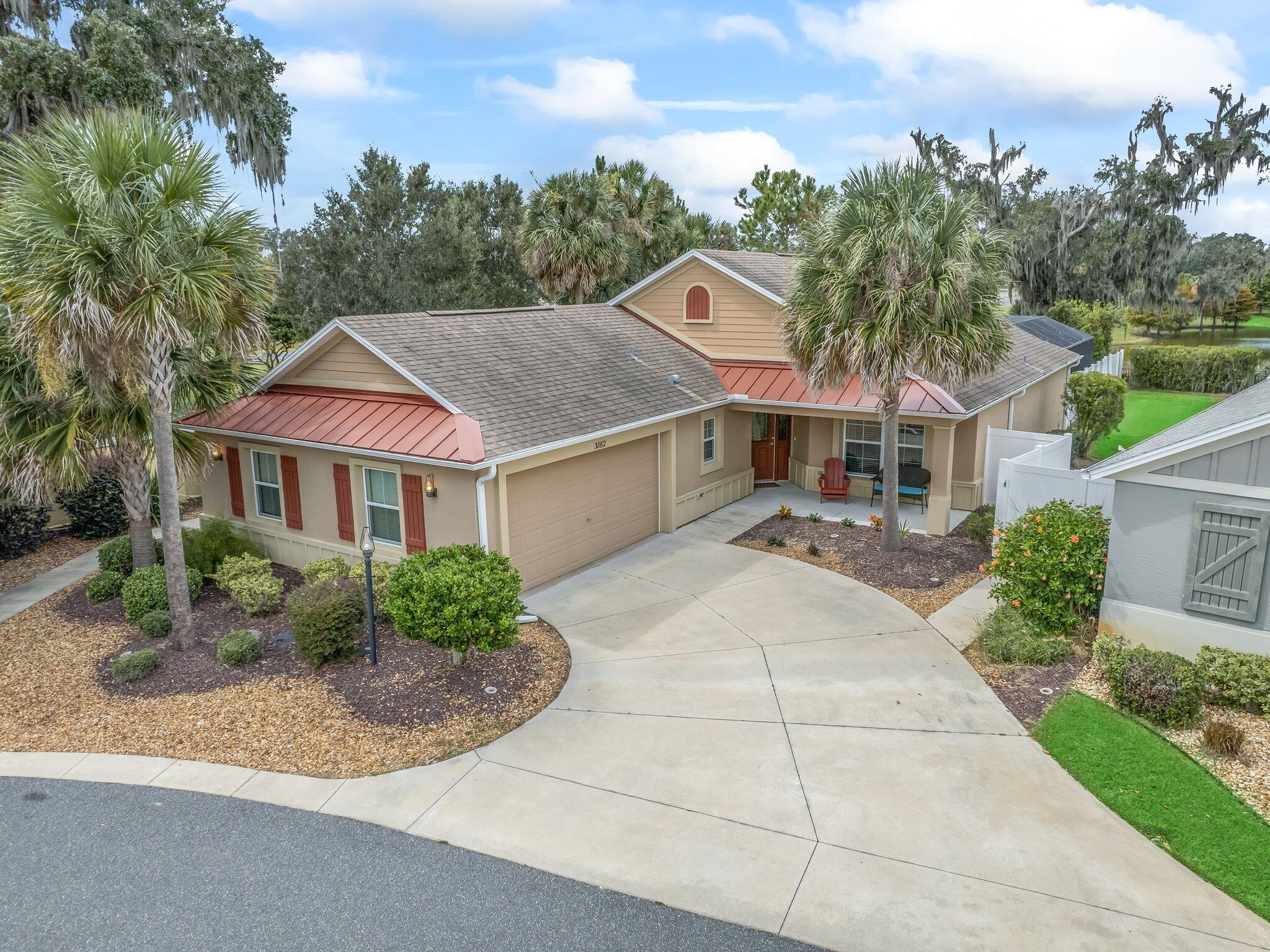 A two-story house with a red roof, beige siding, and a front porch.