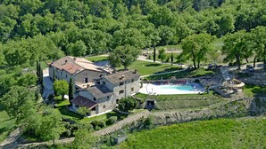 A large stone house with a swimming pool, surrounded by lush greenery and trees. - Agriturismo Vecchia Quercia (Poppi)