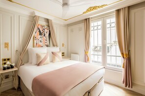 Ein geräumiges Schlafzimmer mit einem großen Bett, einem Nachttisch mit Lampe und einem Fenster mit Vorhängen.