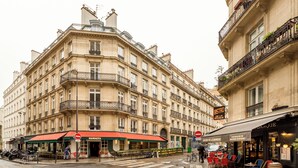 Une vue de rue avec un café appelé « MAMACIT » et une banque appelée « BANQUE ».