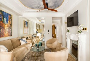 A spacious living room with a high ceiling, a fireplace, and a large mirror reflecting the room.