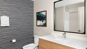 A modern bathroom with a striped wall, a large mirror, a white toilet, and a wooden vanity. - 1BD/Atlanta - Downtown w/Rooftop Pool and Pool Bar! (Atlanta)