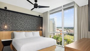 A modern hotel room with a large bed, a desk, a ceiling fan, and a city view. - 1BD/Atlanta - Downtown w/Rooftop Pool and Pool Bar! (Atlanta)