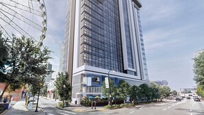 A modern high-rise building with a glass facade, located near a Ferris wheel. - 1BD/Atlanta - Downtown w/Rooftop Pool and Pool Bar! (Atlanta)