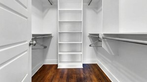 Un petit dressing étroit avec des murs blancs, un plancher en bois et de nombreuses étagères.