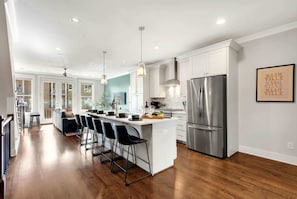 A modern kitchen with a central island, stainless steel appliances, and a bar area with stools. - Summer game room, chef’s kitchen, garage parking near Broadway & Gulch (Nashville)