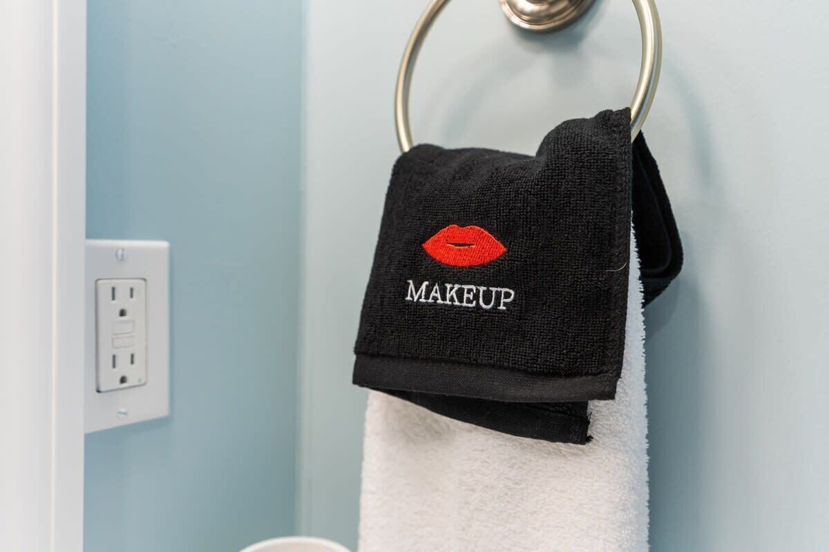 A black towel with a red lip design and the word "MAKEUP" hanging on a metal ring.