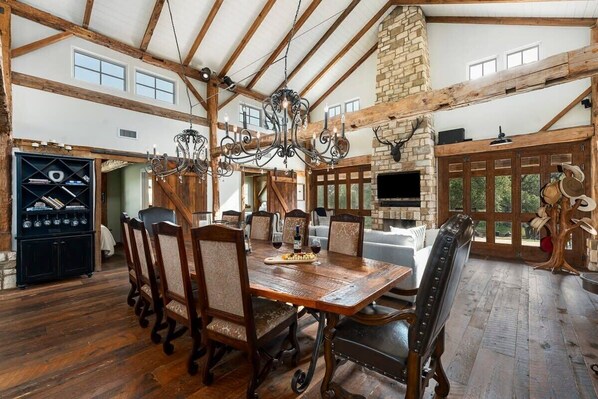 Une salle à manger spacieuse avec une table et des chaises en bois, un lustre et une cheminée en pierre.