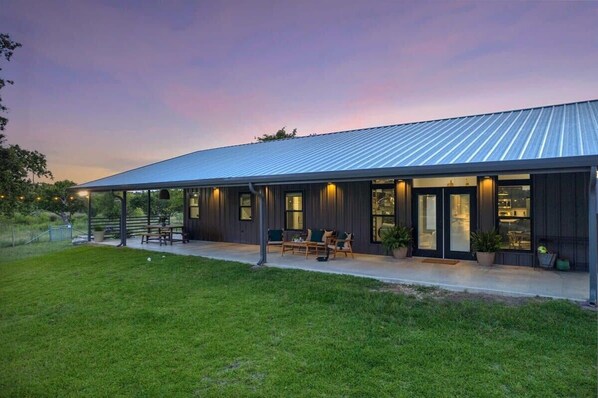 A modern building with a covered patio area, outdoor seating, and potted plants. - Circle A Ranch, Hot tub, Pet Friendly! (Fredericksburg)