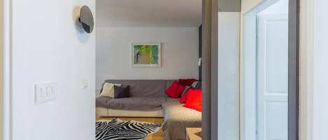 A living room with a grey sofa, red cushions, a zebra rug, and a painting on the wall.