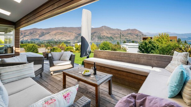Une terrasse sur le toit, aménagée avec du mobilier d’extérieur, une grande fenêtre et une vue sur les montagnes.