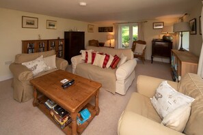 A cozy living room with a beige sofa, a wooden coffee table, and a bookshelf.