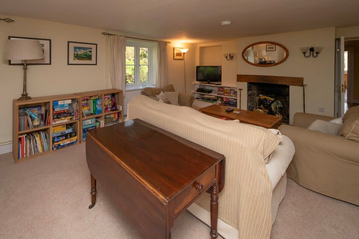 Un salon chaleureux avec un canapé, une table basse en bois, une cheminée, un téléviseur et une bibliothèque remplie de livres.