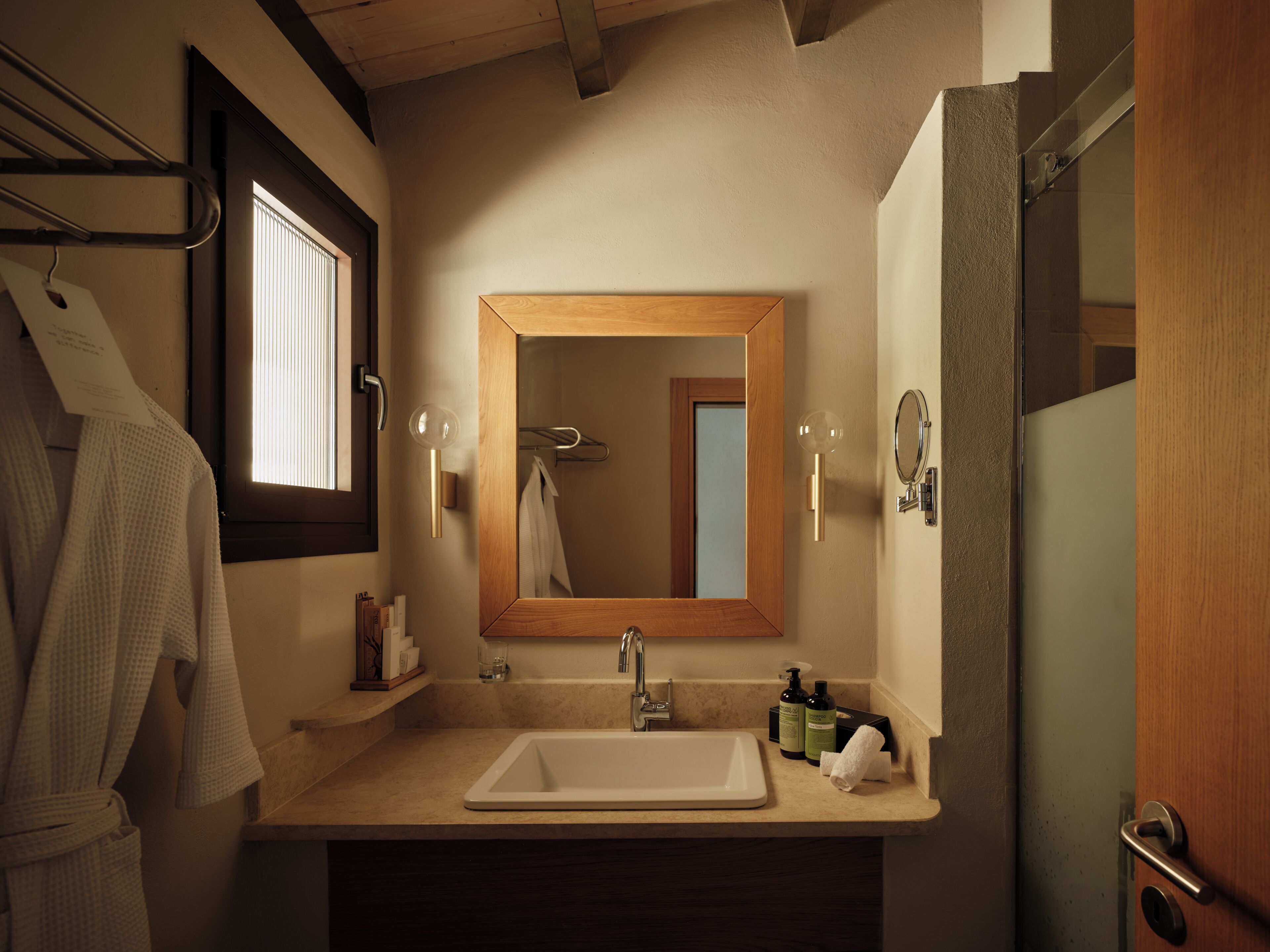 A bathroom with a wooden-framed mirror, a white sink, and a towel rack.