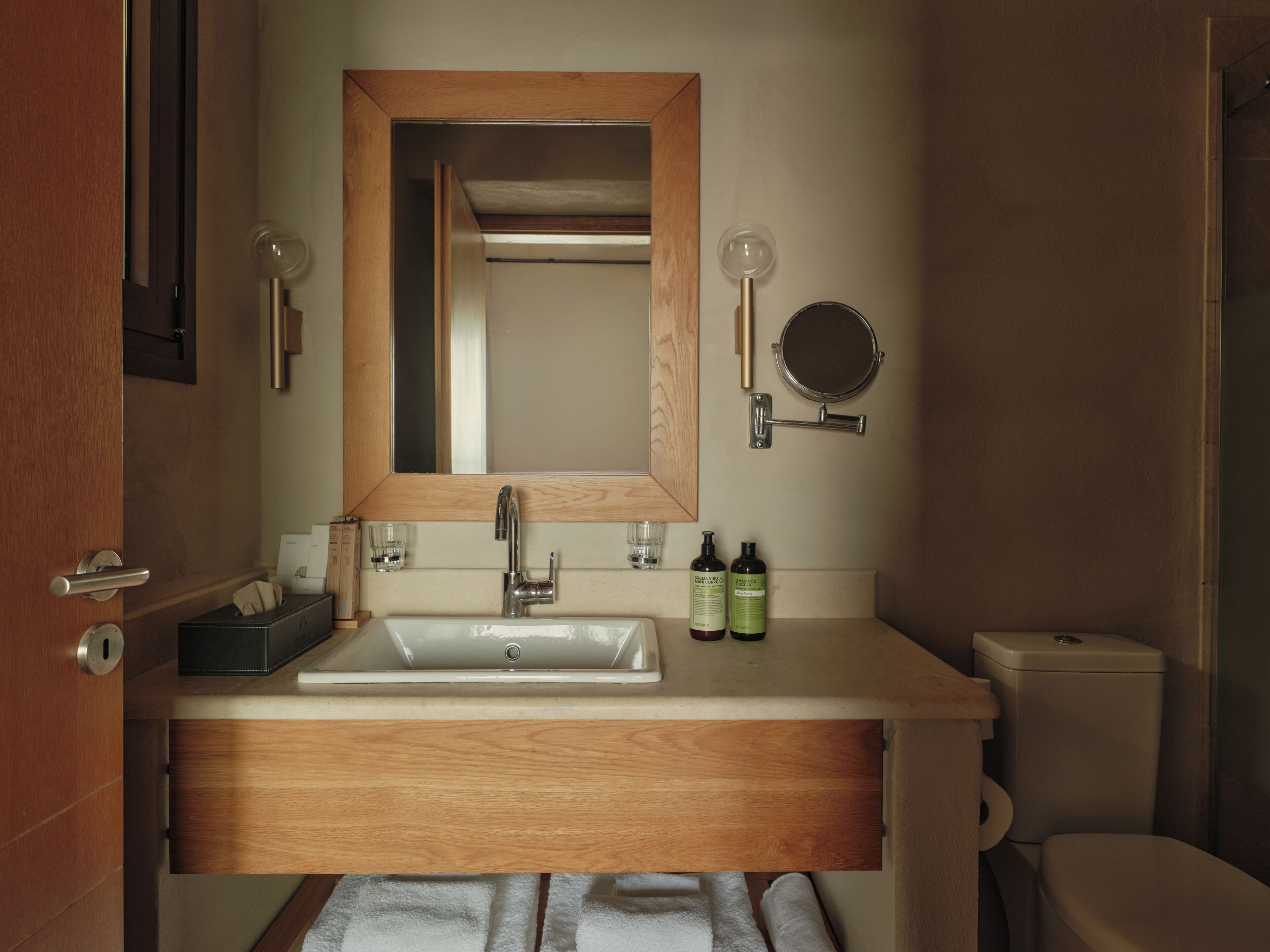 Un baño con tocador de madera, un lavabo, un espejo y un inodoro.
