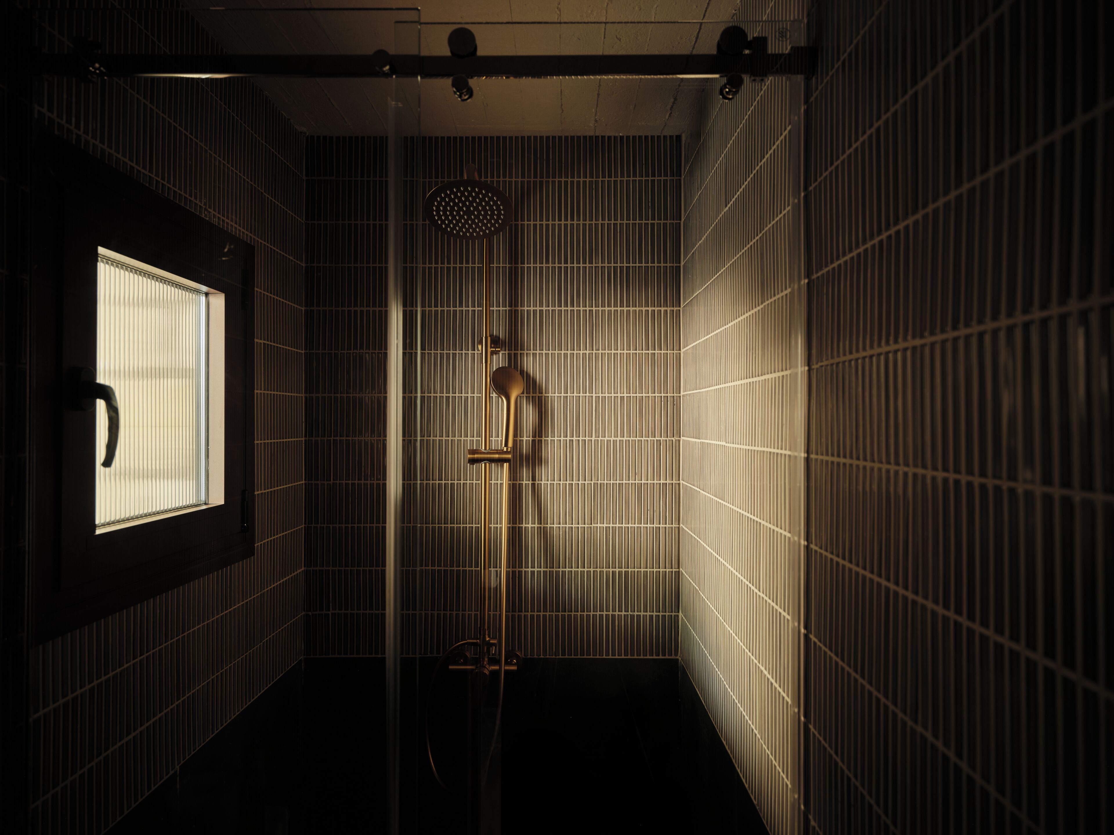 A bathroom with a window, a shower, and a towel rack.