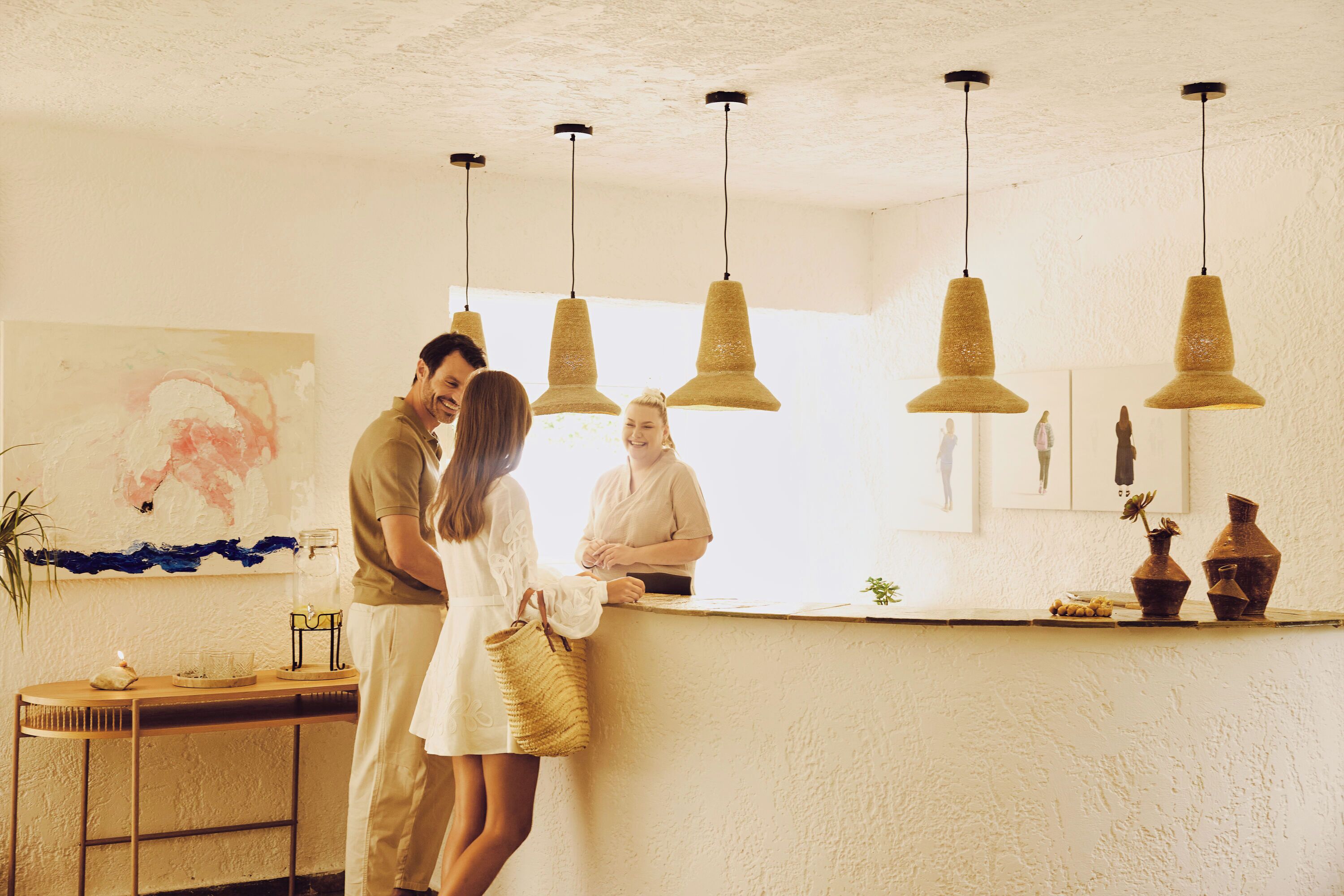 Een receptie met een houten balie, hangende pendantlampen en een schilderij aan de muur.