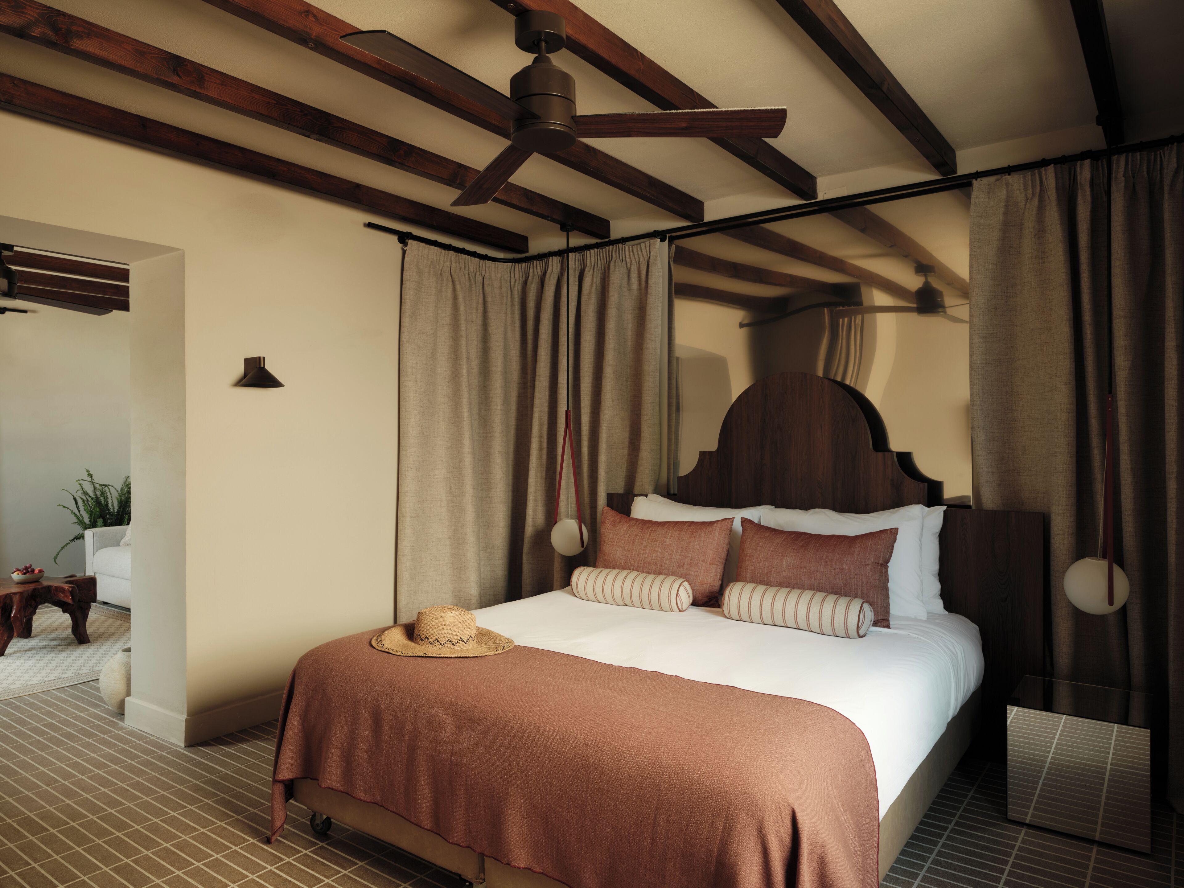 Une chambre d’hôtel avec un lit, un ventilateur de plafond, des rideaux et un plafond en bois.