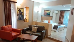 A hotel room with a sofa, armchair, and a bed. - La Cour - Hotels (Lagos)