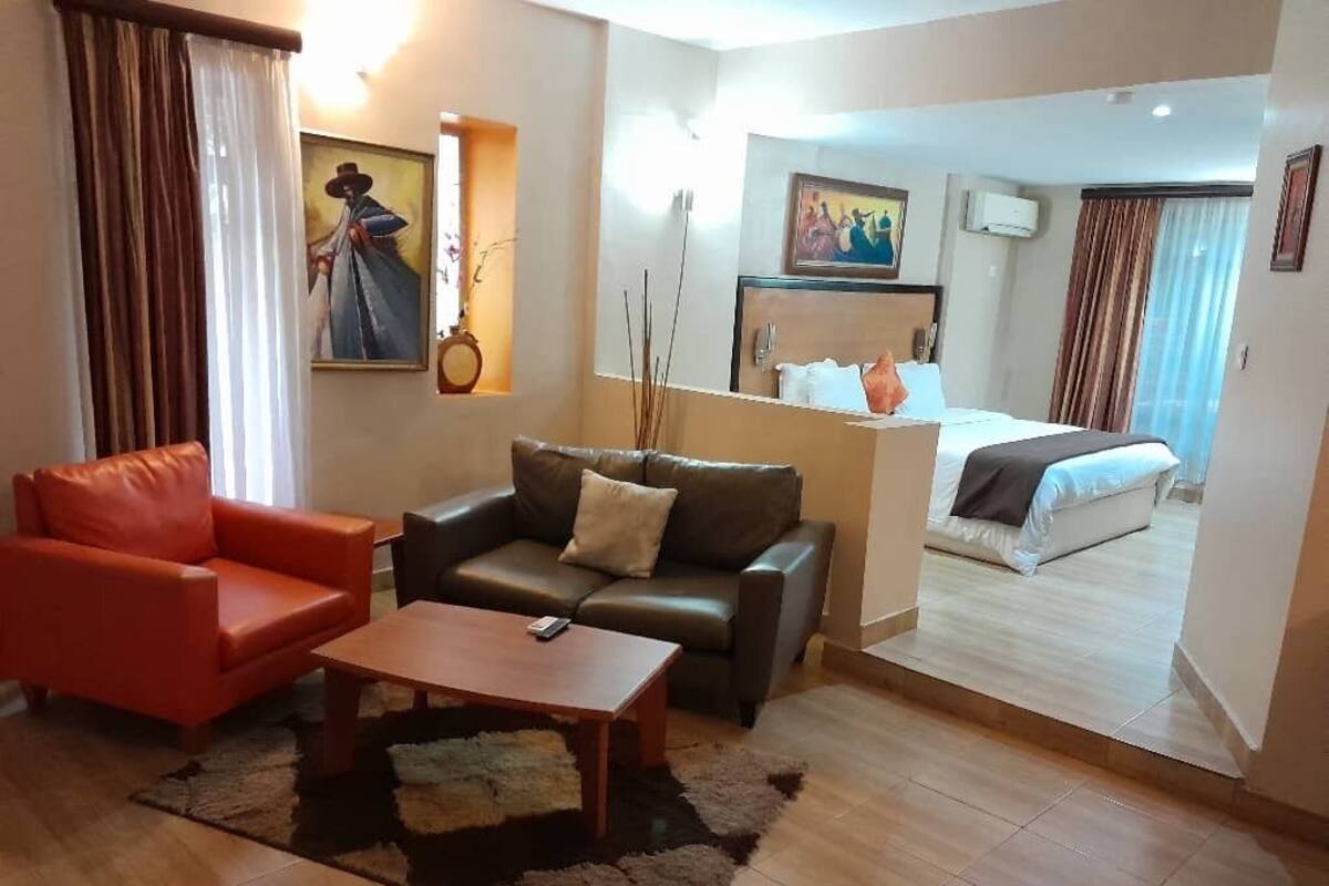 A hotel room with a sofa, armchair, and a bed.