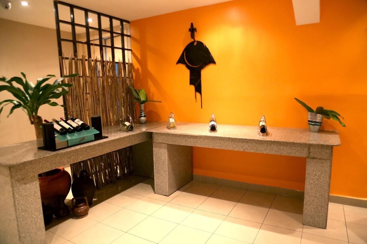 A reception area with a stone counter, potted plants, and a decorative wall with a silhouette.
