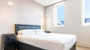 Une chambre moderne avec un grand lit, une table de chevet et une fenêtre donnant sur la ville.