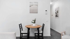 Un coin repas avec une table ronde, deux chaises et une plante en pot.