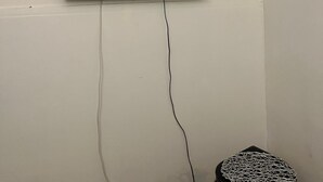 A flat-screen TV mounted on a white wall with a visible power cord. - Perfect Stopover 30 Min from Airport Central, Abu Dhabi (Abu Dhabi)