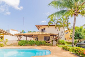A residential property with a swimming pool, a covered patio, and a car parked nearby.