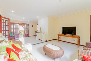 Una sala de estar con televisor, muebles de mimbre y una mesa decorativa.