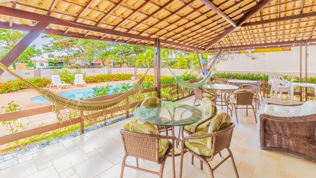 An outdoor patio area with wicker furniture, a glass table, and a hammock.