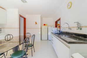 Una cucina compatta con angolo ristoro, un frigorifero, un lavello e una sveglia appesa al muro.