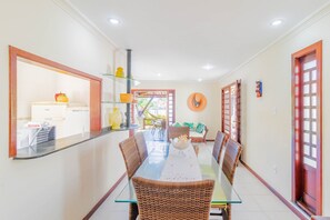 A dining area with a glass table, wicker chairs, and a view of the outside.
