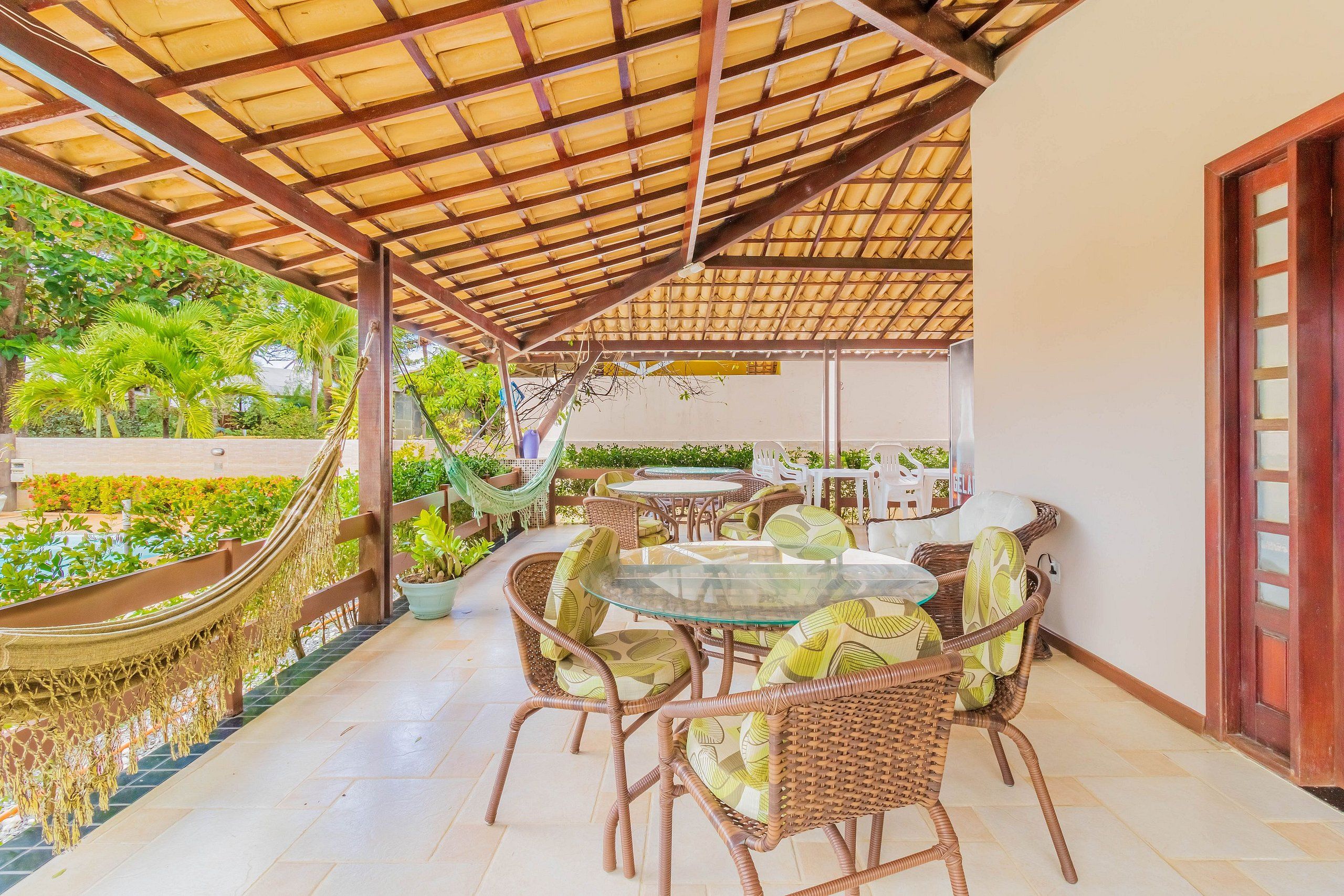 Ein Außenbereich mit Terrassengestaltung, Rattanmöbeln, einem Pool und einem überdachten Bereich mit Holzdach.