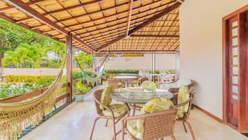 Ein Außenbereich mit Terrassengestaltung, Rattanmöbeln, einem Pool und einem überdachten Bereich mit Holzdach.
