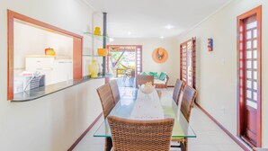 A dining area with a glass-top table, wicker chairs, and a central island with a bowl.