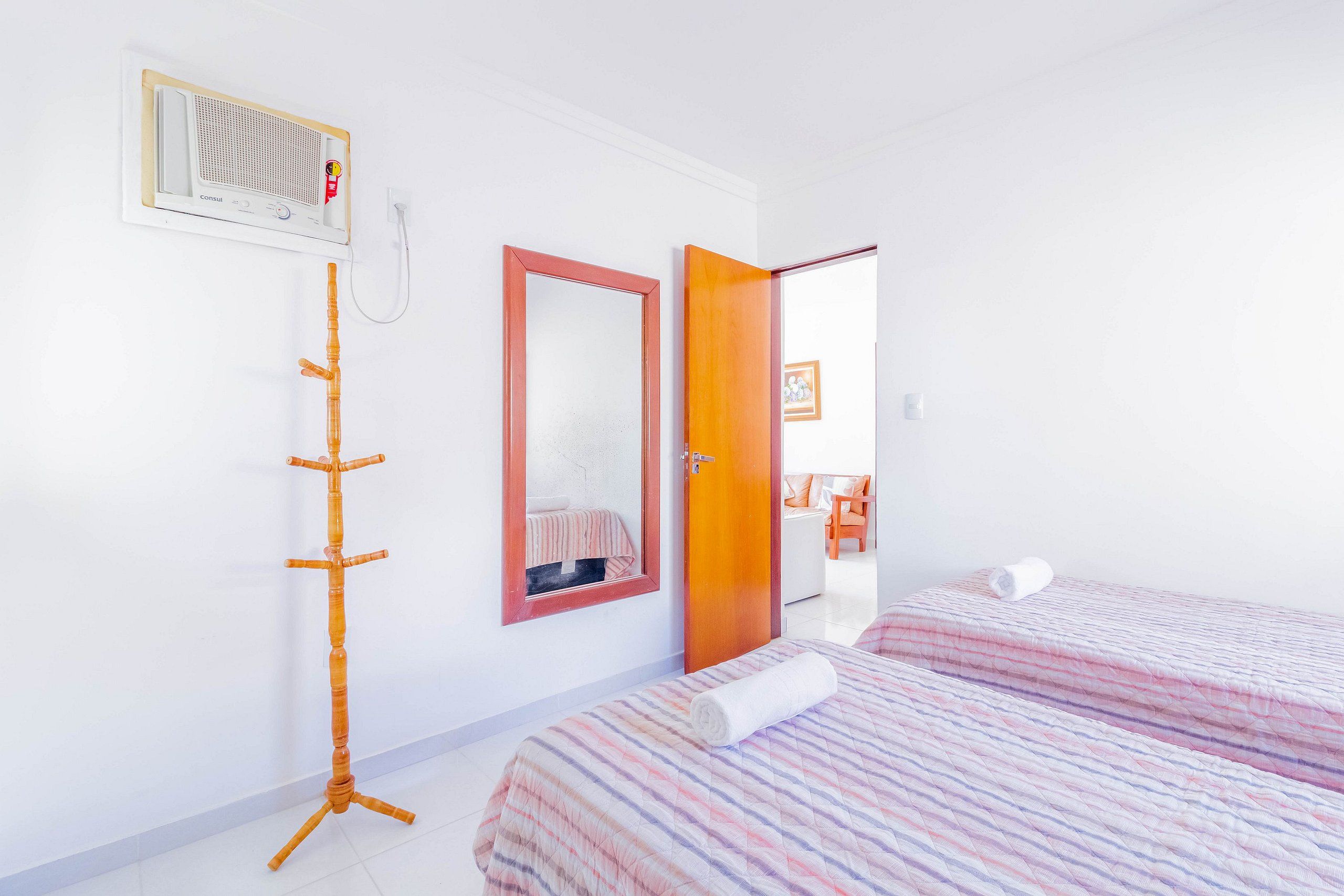 Habitació d'hotel amb un llit, una taula de nit, un mirall, un radiador i una porta que dona a una altra habitació.