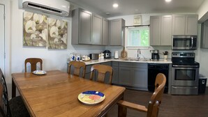 A modern kitchen with grey cabinets, stainless steel appliances, and a dining area with a wooden table and chairs. - Swim, fish, and explore bluffs, just across the street. (Lowell)