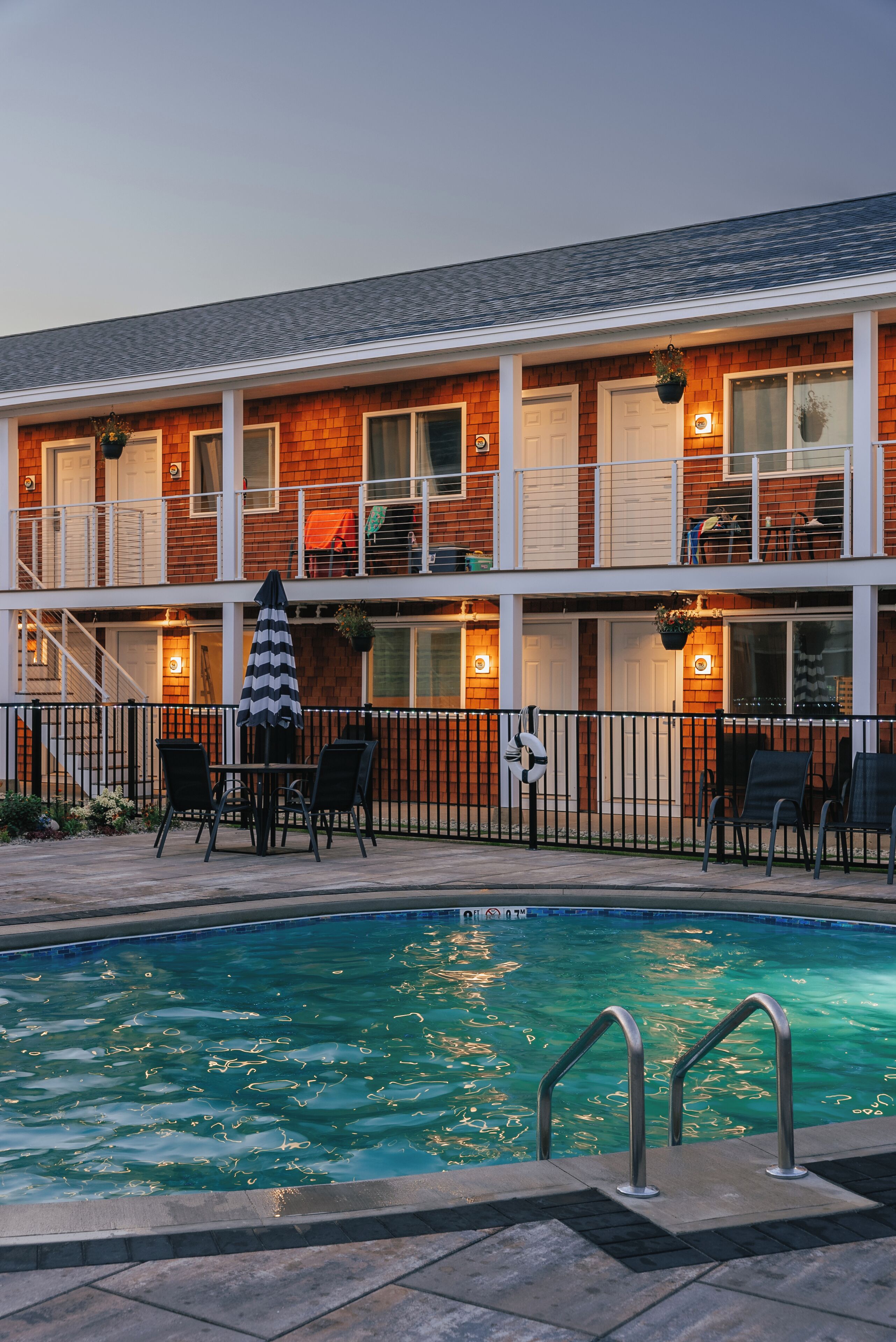 Un hotel con piscina, mobiliario exterior y una estructura de dos pisos.