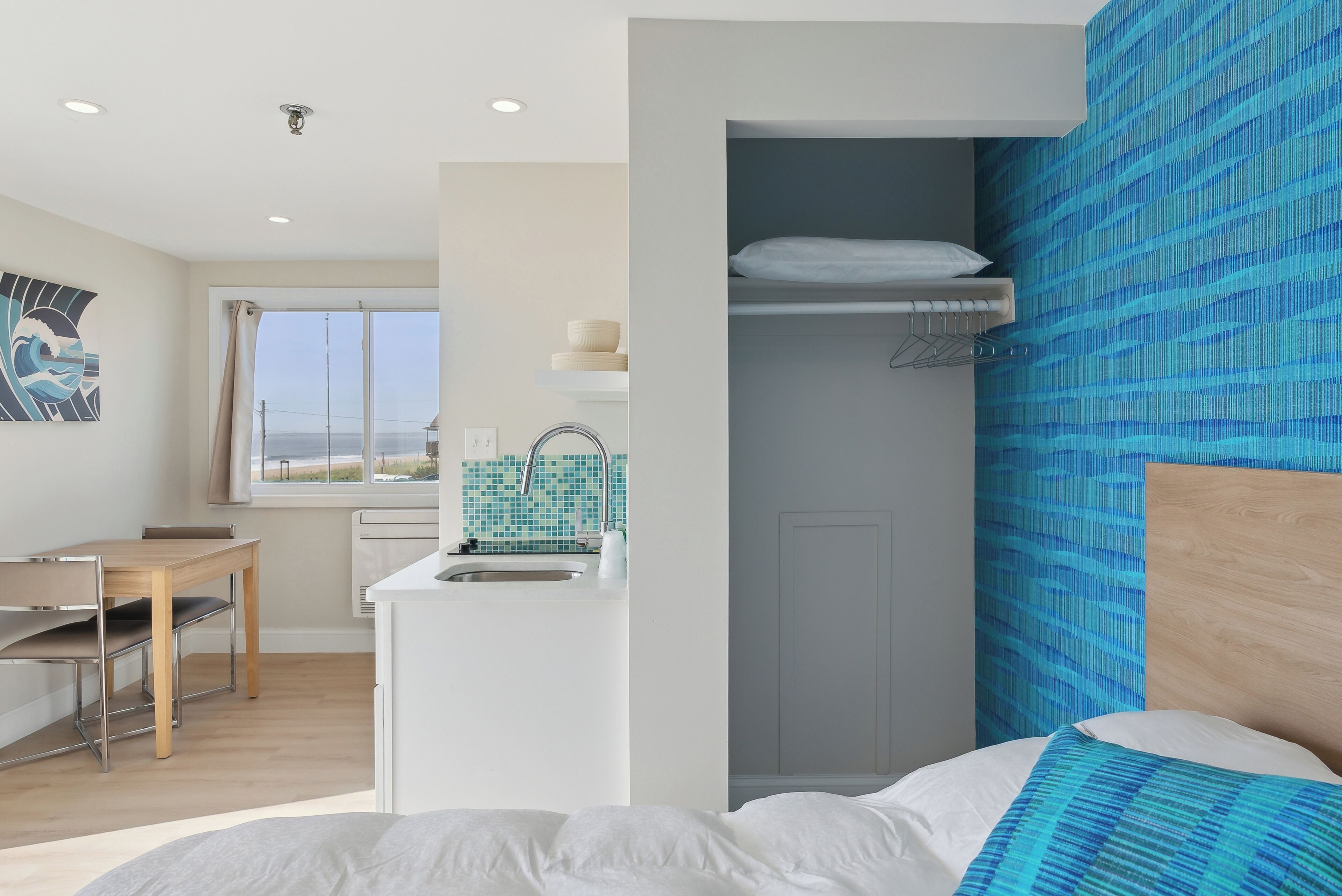 Una habitación con cama, escritorio, kitchenette y vistas al exterior.