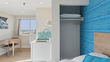 Una habitación con cama, escritorio, kitchenette y vistas al exterior.