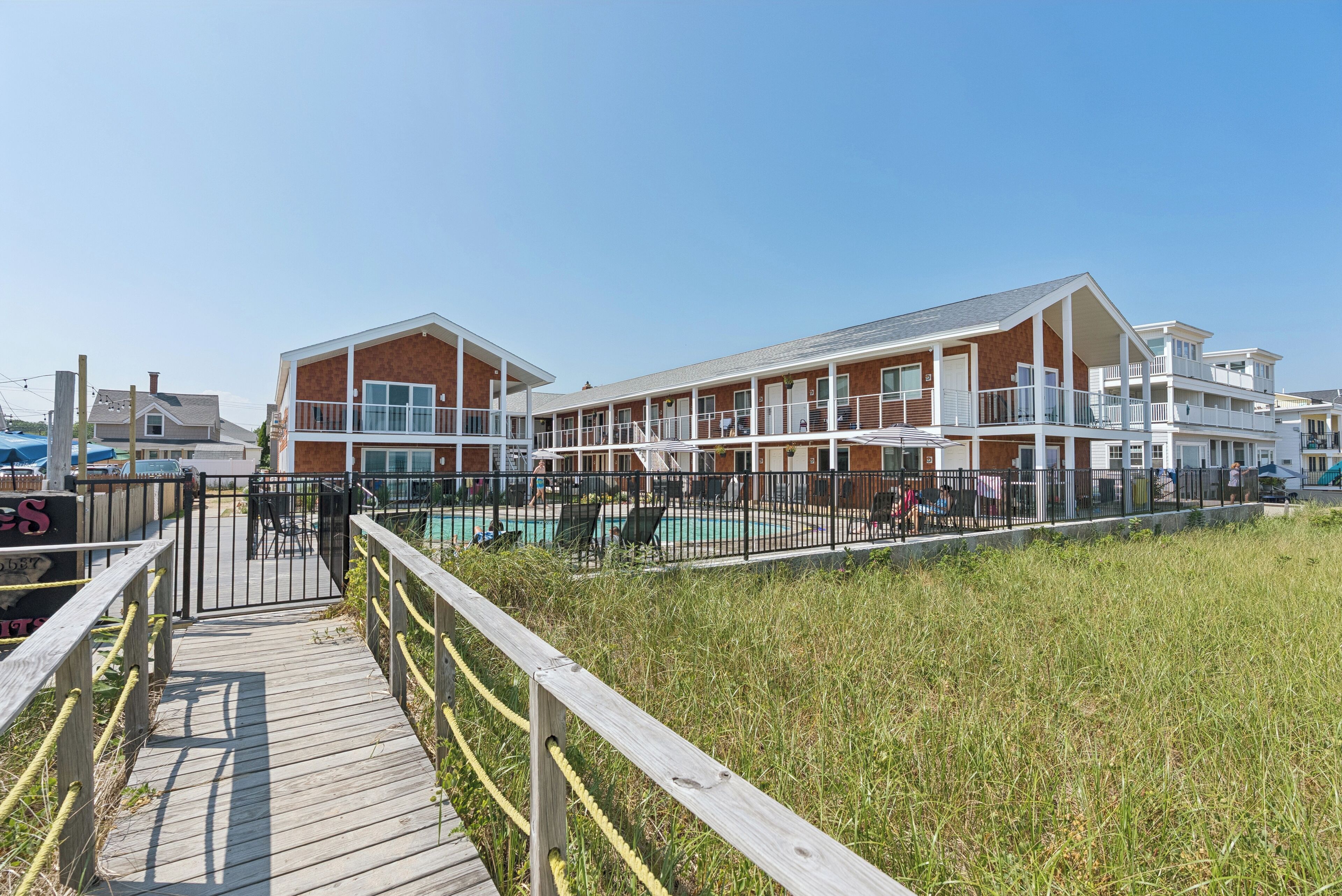A beachfront hotel with a pool area, wooden deck, and multiple balconies.