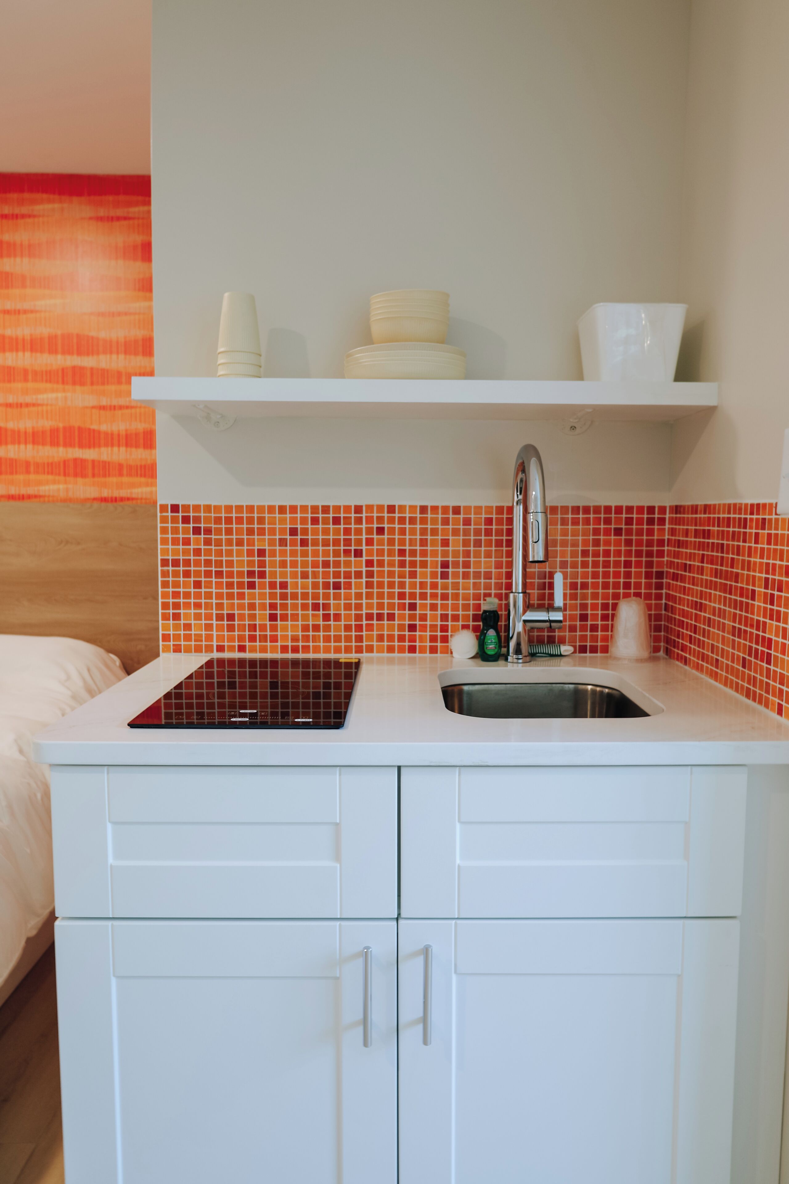 A compact kitchenette with a sink, a stovetop, and a small countertop.