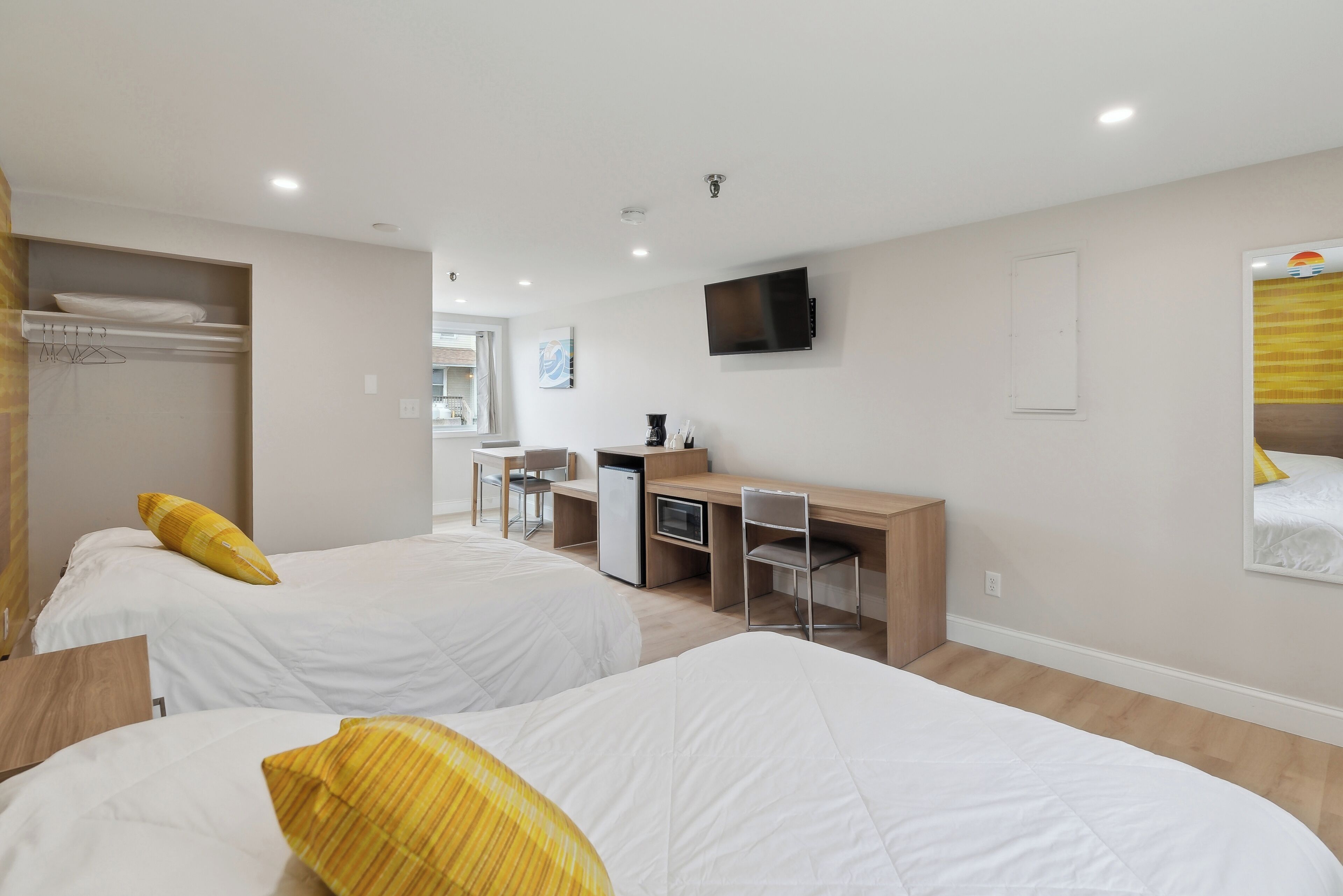 A hotel room with two beds, a desk, a chair, a TV, and a wardrobe.