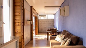 A modern living room with a wooden floor, a brown sofa, and a dining area with a table and chairs. - Pousada Boschetti (Gramado)
